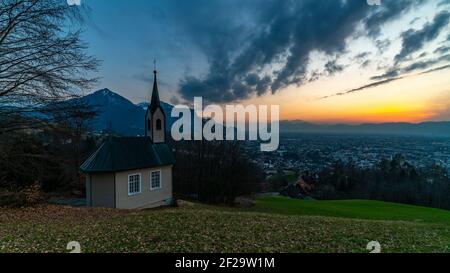 Schöner Sonnenuntergang und Nachglühen in Dornbirn mit Wolken, die auf die Rhomberkapelle zeigen, farbiger Himmel über Rheintal, Staufenspitze, Säntis Stockfoto