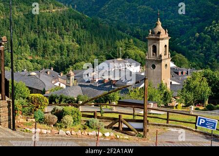 Überblick über kleines Bergdorf mit zentralem Kirchturm umgeben Durch grüne Wälder Stockfoto