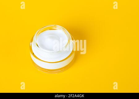 Gesichtscreme in einem Glas Nahaufnahme. Flasche kosmetische Creme auf gelbem Hintergrund mit Platz für Text. Hautpflegekonzept, natürliches Beauty-Produkt Stockfoto