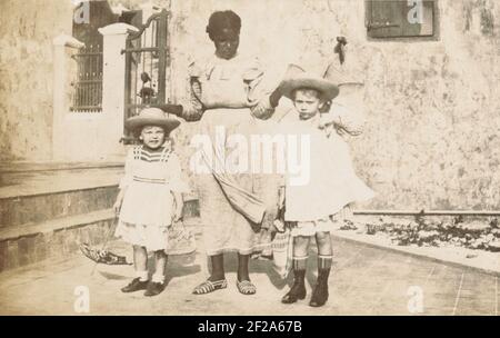 Ernita en Maria de Vries.Porträt der beiden kleinen Schwestern Ernita und Maria de Vries zusammen mit einem Kindermädchen, auf Curaçao, Januar 1912. Teil des Fotoalbums der Familie Boom-Gonggrijk in Suriname und Curaçao. Stockfoto