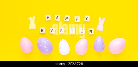 Grußkarte mit Text Frohe Ostern. Bunte ostereier und Papierkaninchen auf gelbem Hintergrund - Bild Stockfoto