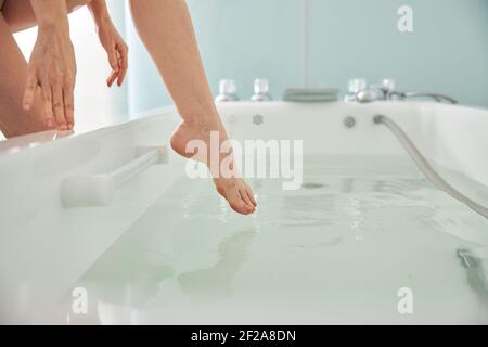 Person, die ein Bein in ein Spa-Bad mit Wasser Stockfoto