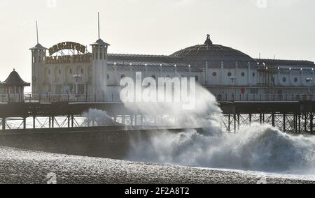 Brighton UK 11th March 2021 - Wellen stürzen heute am Brighton Palace Pier auf den Strand, als stürmisches Wetter die Südküste schlägt : Credit Simon Dack / Alamy Live News Stockfoto