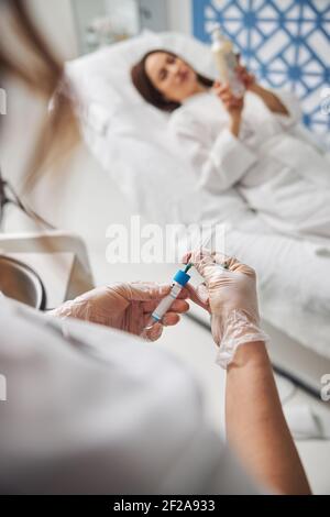 Ärztin Hände halten Reagenzglas und Nadel Stockfoto