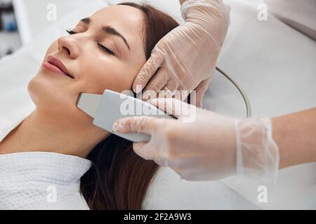 Lächelnde Frau, die Gesichtsbehandlung in der Kosmetologie Klinik Stockfoto