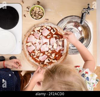 Hausmannskost. Kinder machen Leuchtfeuer und Pilze Pizza in Spielzeug Küche Overhead Blick Stockfoto