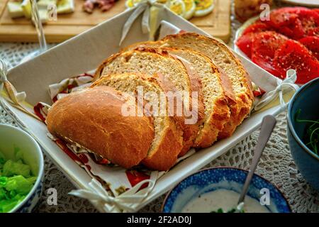 Ein Brot in Scheiben geschnitten. Ein kontinentales, gesundes Frühstück mit hausgemachtem Brot und einem Gemüse, Käse und Ei. Brot auf Dinkelbasis und Stockfoto