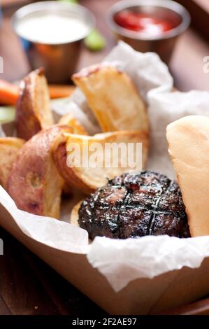 Ethisch angehobener Schweinefleischburger mit handgeschnittenen roten Kartoffelkeilen Und Gemüsestöcke nehmen Stock Foto Stockfoto