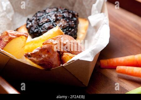 Ethisch angehobener Schweinefleischburger mit handgeschnittenen roten Kartoffelkeilen Und Gemüsestöcke nehmen Stock Foto Stockfoto