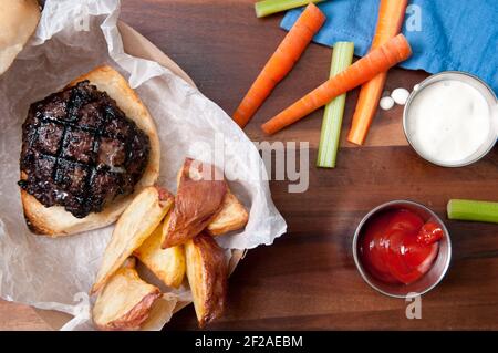 Ethisch angehobener Schweinefleischburger mit handgeschnittenen roten Kartoffelkeilen Und Gemüsestöcke nehmen Stock Foto Stockfoto