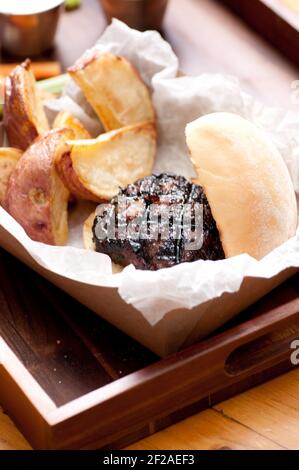 Ethisch angehobener Schweinefleischburger mit handgeschnittenen roten Kartoffelkeilen Und Gemüsestöcke nehmen Stock Foto Stockfoto