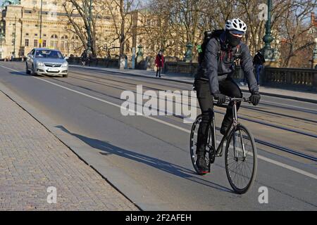 Prag, Tschechische Republik - April 3 2020: Radlieferer mit Schutzschal fährt während des Coronavirus Covid-19 Ausbruchs auf der Straße Stockfoto