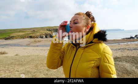 Reife Frau mit einem Inhalator an einem Strand Lage - John Gollop Stockfoto