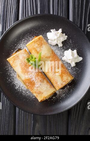 Palatschinken Österreichische Crepes mit Aprikosenmarmelade in Nahaufnahme auf einem Teller auf dem Tisch. Vertikale Draufsicht von oben Stockfoto