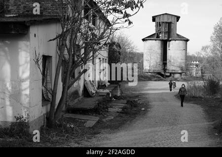 Prag, Tschechische Republik - April 15 2020: Menschen mit Schutzmaske auf der Moldau Seite, verlassene Gebäude schwarz-weiß Foto Stockfoto