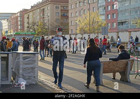 Prag, Tschechische Republik - April 15 2020: Coronavirus Covid-19 Szene : Menschen mit Schutzmaske und sicherer Entfernung warten lange Schlange vor Stockfoto