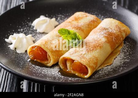 Palatschinken Österreichische süße Pfannkuchen mit Aprikosenmarmelade in Nahaufnahme in einem Teller auf dem Tisch. Horizontal Stockfoto