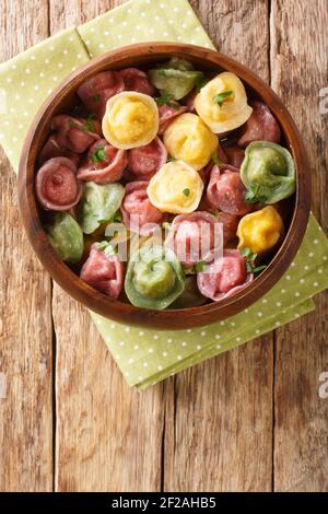 Italienische Pasta Tortellini aus gefärbten Teig Nahaufnahme in einer Schüssel auf dem Tisch. Vertikale Ansicht von oben Stockfoto