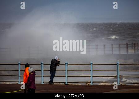 Morecambe Lancashire, Großbritannien. März 2021, 11th. Spaziergänger beobachten, wie ein Fotograf ein Foto von den Wellen bricht über die Grosvenor Fishing Jetty in High Tide an diesem Morgen Quelle: PN News/Alamy Live News Stockfoto