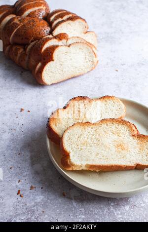 Frisch geschnittenes Challah-Brot mit zwei gerösteten Scheiben auf einem Teller. Stockfoto