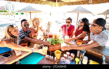 Junge trendige Leute toasten an der Strand-Cocktailbar Chiringuito mit Offene Maske - Neue normale Sommer-Lifestyle-Konzept mit Freunde haben Spaß zusammen Stockfoto