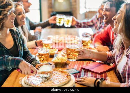 Junge Freunde essen Pizza zu Hause auf Winter-Wiedersehen - Freundschaftskonzept mit glücklichen Menschen, die Zeit miteinander genießen und haben Spaß trinken brauen Pints Stockfoto