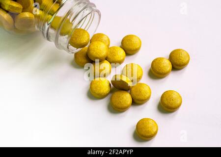 Gelbe Pillen und Tabletten verschüttet aus Glas Pille Flasche Auf weißem Hintergrund Stockfoto