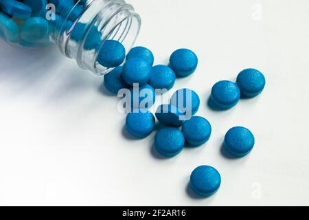 Blaue Pillen und Tabletten verschüttet aus Glas Pille Flasche Auf weißem Hintergrund Stockfoto