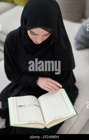 Porträt einer jungen muslimischen Frau beim Lesen des Quran in einem modernen Zuhause Stockfoto