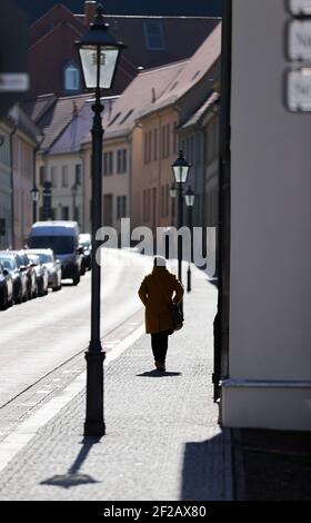 11. März 2021, Sachsen-Anhalt, Köthen: Eine Frau im Sonnenschein spaziert durch die historische Innenstadt. Foto: Jan Woitas/dpa-Zentralbild/dpa Stockfoto