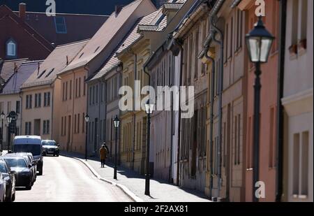 11. März 2021, Sachsen-Anhalt, Köthen: Eine Frau im Sonnenschein spaziert durch die historische Innenstadt. Foto: Jan Woitas/dpa-Zentralbild/dpa Stockfoto