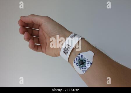 Krankenhausschild am Handgelenk mit EKG-Pad, weiß kaukasisch, weiß, blasse Haut, id-Tag, Krankenhausetikett, ekg-Pad, Handfläche, rechte Hand, Finger, Handgelenk Stockfoto