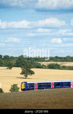 Personenzug der Klasse 377 in der First Capital Connect Lackierung, die durch die englische Landschaft rast. Stockfoto