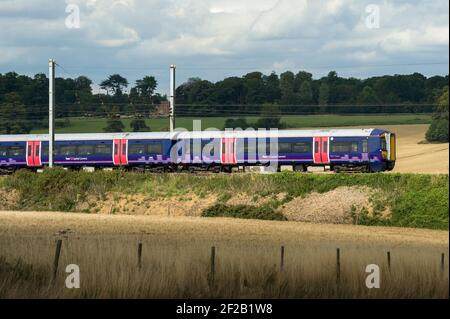 Personenzug der Klasse 377 in der First Capital Connect Lackierung, die durch die englische Landschaft rast. Stockfoto
