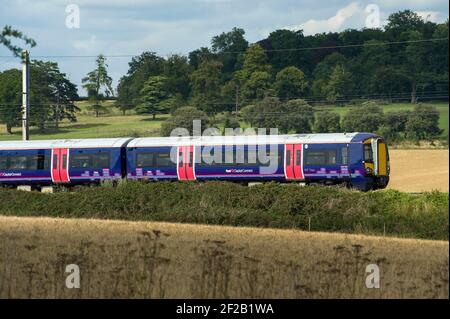 Personenzug der Klasse 377 in der First Capital Connect Lackierung, die durch die englische Landschaft rast. Stockfoto