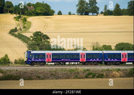 Personenzug der Klasse 377 in der First Capital Connect Lackierung, die durch die englische Landschaft rast. Stockfoto