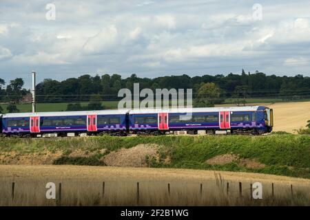 Personenzug der Klasse 377 in der First Capital Connect Lackierung, die durch die englische Landschaft rast. Stockfoto