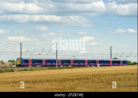 Personenzug der Klasse 377 in der First Capital Connect Lackierung, die durch die englische Landschaft rast. Stockfoto
