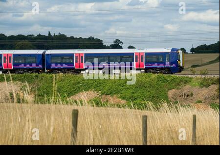 Personenzug der Klasse 377 in der First Capital Connect Lackierung, die durch die englische Landschaft rast. Stockfoto