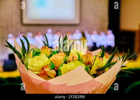 Blumenstrauß zum Gratulieren des Sängers. Schöne Blumen für den Teilnehmer des Gesangswettbewerbs. Rosenstrauß im Musiksaal. Stockfoto