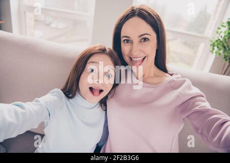 Portrait von positiven funky Dame kleines Mädchen machen Selfie haben Spaß Zunge aus Verbringen Sie Freizeit Wochenende zu Hause drinnen Stockfoto