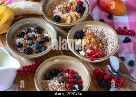 Stillleben von Familienfrühstück mit Haferflocken, Müsli, Müsli und Müsli gekrönt mit Obst und Nüssen und serviert in rustikalen Schalen Stockfoto