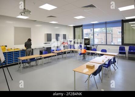 Ein Kunstlehrer arbeitet allein in einem Klassenzimmer in einer neu aufgebauten Grundschule im Süden Londons, Großbritannien. Stockfoto