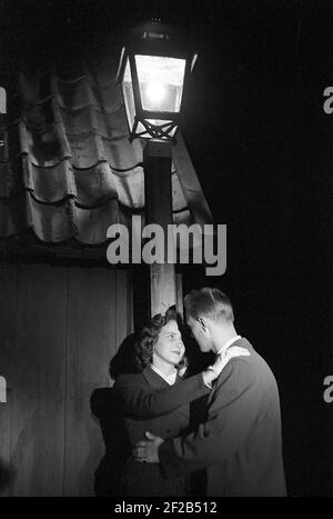 Liebe in der 1950s. Ein junges Paar steht am Abend unter einer Straßenlaterne und küsst sich. Schweden 1953 Ref. Pärm 1 Stockfoto