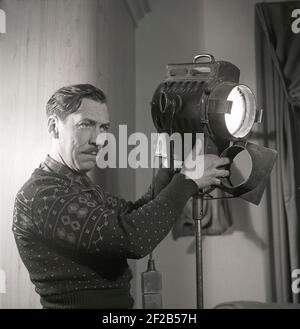 Filmstudio in der 1940s. Ein Mann, der am Filmset arbeitet, handhabt die Lampe, mit der die Filmszene während der Dreharbeiten zum Film Sjätte budet beleuchtet wird. Schweden 1947. ref. AA6-1 Stockfoto