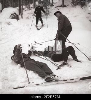 Winter in der 1940s. Eine Gruppe von Leuten, die Skifahren und sie haben Probleme, direkt auf ihnen stehen. Ein Mann versucht, eine helfende Hand zu geben, um wieder zu stehen. Schweden 1947. Kristoffersson Ref. AA30-9 Stockfoto