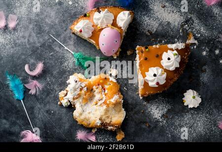 Blick in den Hochwinkel von einigen Stücken einer mona de pascua, einem Kuchen, der am Ostermontag in Spanien gegessen wurde, verziert mit einem rosa Ei und Federn in verschiedenen Farben Stockfoto