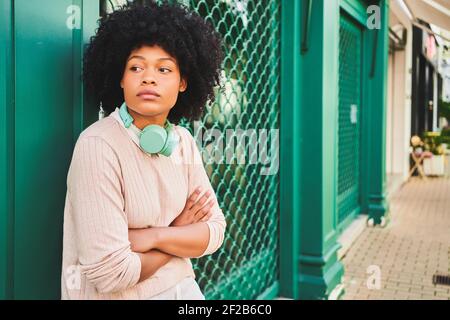 Latina Frau mit afro Haar mit gekreuzten Armen. Horizontales Porträt einer afroamerikanischen Frau. Hochwertige Fotos Stockfoto