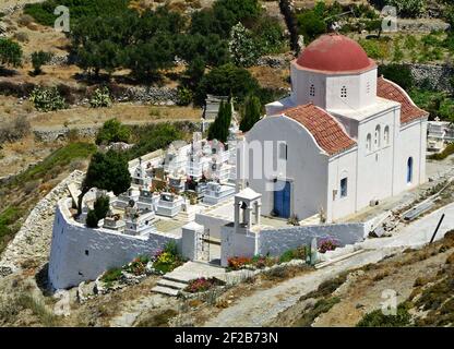Landschaft mit Blick auf eine griechisch-orthodoxe Kirche und Friedhof in der Landschaft der Insel Karpathos in Dodekanes, Griechenland. Stockfoto