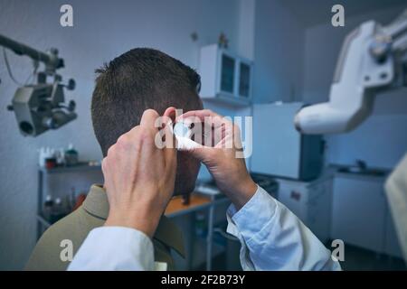 Patient in der HNO-Klinik. Facharzt - Otolaryngologe, der Ohrenuntersuchung des jungen Mannes macht. Stockfoto